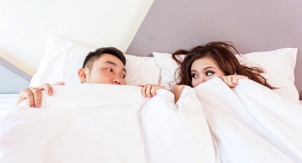 Seasonal Changes. Young couple napping in bed with white sheets